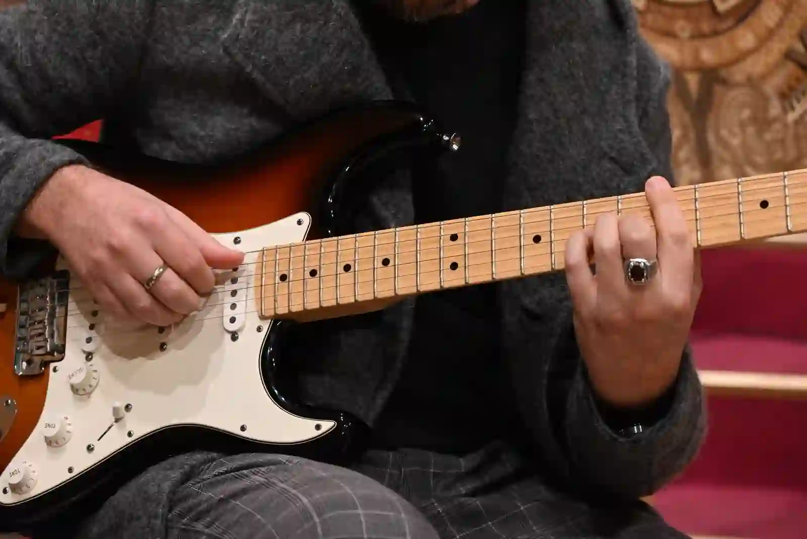 Mani in primo piano sulla chitarra Fender Stratocaster, dettaglio tecnico